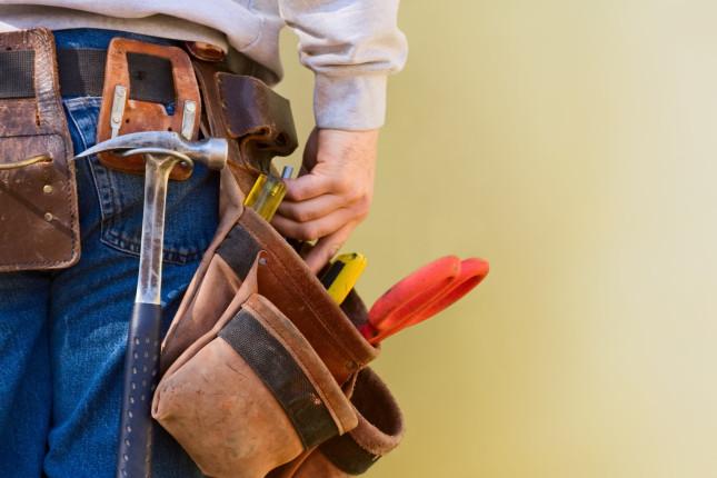 A young construction worker reaches into his tool belt. Copy Space.